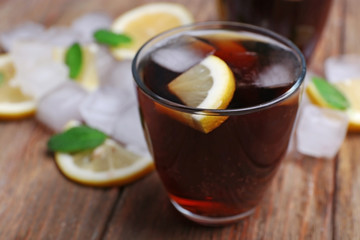 Glass of cola with cubes of ice and lemon on wooden table background, closeup