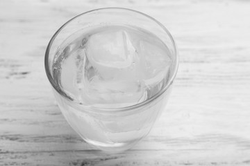 Glass of water with ice on white wooden table background