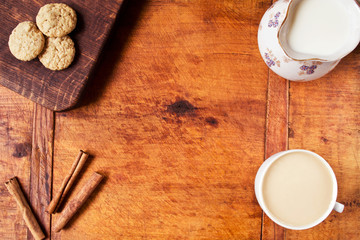 Food frame with coffee, milk, cinnamon and oatmeal cookies on wooden table 