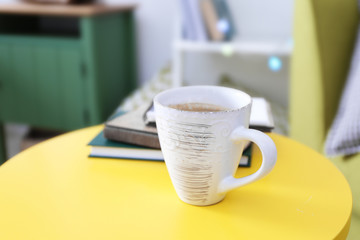 Cup of coffee with books on table in interior of living room