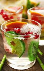 Refreshing cocktails with ice, pomegranate seeds and slices of fruits on wooden background