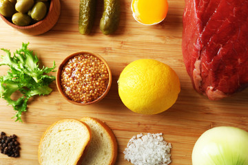 Beef tartare ingredients on wooden cutting board