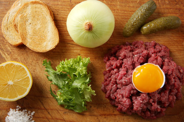 Fototapeta na wymiar Beef tartare ingredients on wooden cutting board