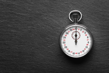 Stopwatch on black textured background, close up