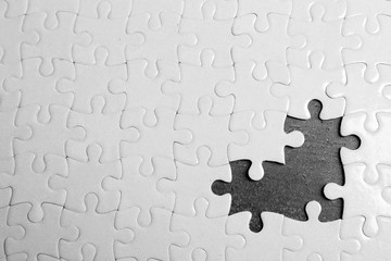 White jigsaw puzzle with missing pieces on grey background