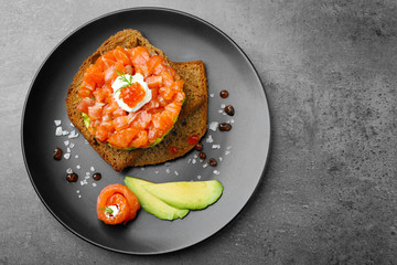 Fresh tartar with salmon, avocado, red caviar and black bread on plate