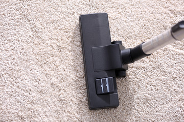 Vacuum cleaner sweeping a white carpet, close up