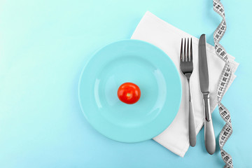 Plate with cherry tomato on table with fork, knife and measuring tape, top view