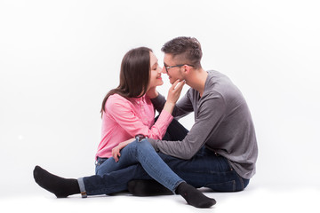 Young hipster man in glasses and woman sitting down and kiss isolated on the blank white background