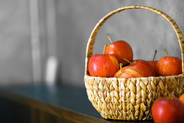 Wicker basket with ripe apples on wooden table