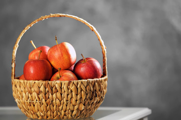 Fototapeta na wymiar Wicker basket with ripe apples on white table