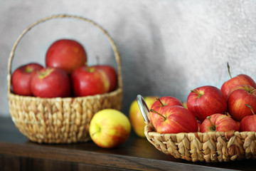 Fototapeta na wymiar Wicker tray with ripe apples on wooden table