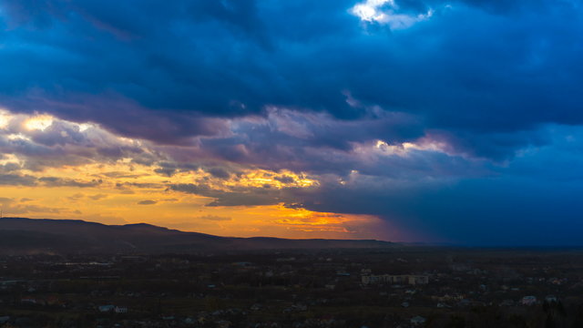 The flow of rain cloud above the city on the sunset background. Time lapse