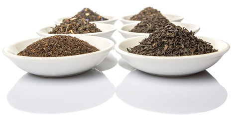 Dried variety of black tea leaves in white bowl over white background