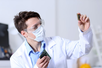 Young man in glasses and mask looking at the computer processor