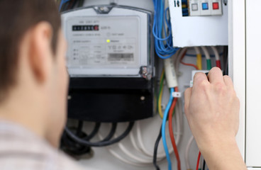 Young electrician checking voltage in fuse board