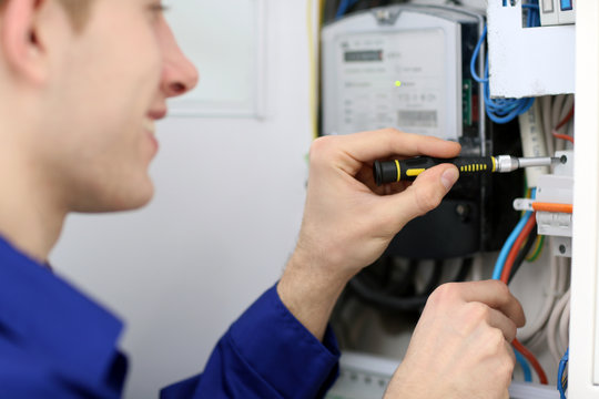 Young electrician working with screwdriver in fuse board