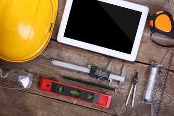 Helmet and tablet on a wooden background.