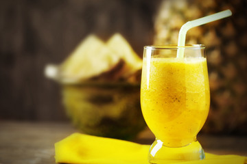 Pineapple smoothie in cocktail glass on wooden background