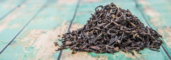 Loose dried darjeeling black tea leaves over wooden background - obrazy, fototapety, plakaty