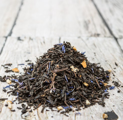 Dried black Earl Grey tea leaves over wooden background