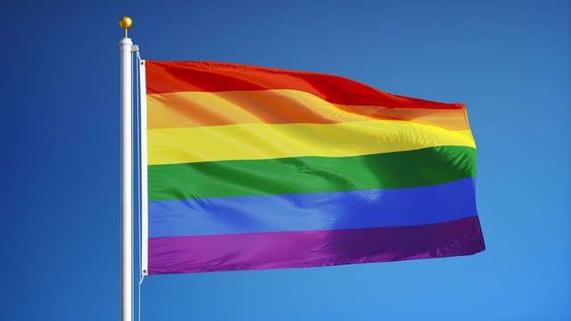 The gay pride rainbow flag waving in slow motion against clean blue sky, seamlessly looped, close up, isolated on alpha channel with black and white luminance matte, perfect for film, news
