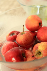 Red apple in glass bowl with water.