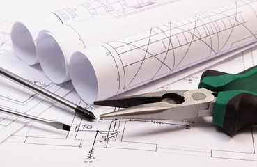 Rolls of diagrams and work tools on electrical construction drawing of house