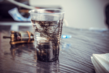 Tattoo ink spreading in the water glass.