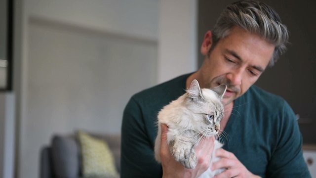 Man at home cuddling beautiful cat