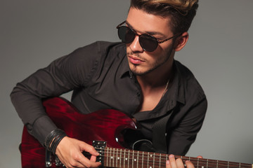 side view of a young man playing an electric guitar