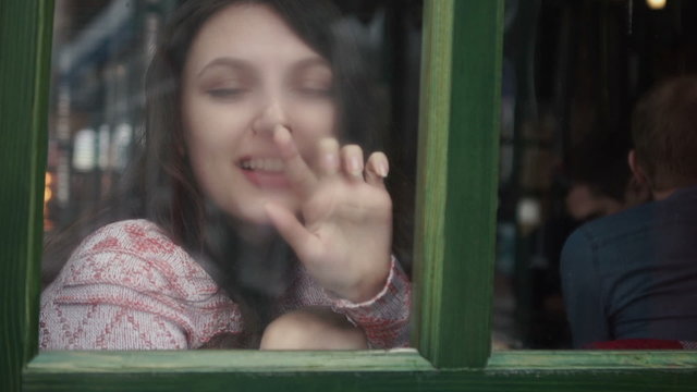 beautiful girl sitting on the window sill and painting on glass 