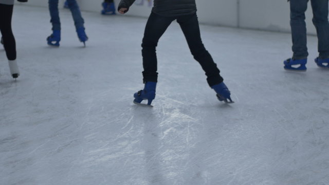 Teen is making  hesitateting steps on ice as he/she is leaninr to ice skate.