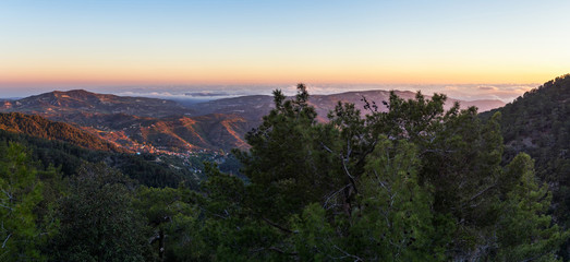 Fototapeta premium Panoramic view on mountain range with layer mist on evening glow background. Troodos, Cyprus. 