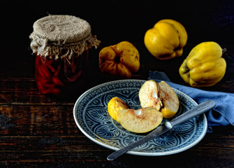 cut fruit quince on a plate, a knife on a wooden background
