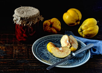 cut fruit quince on a plate, a knife on a wooden background
