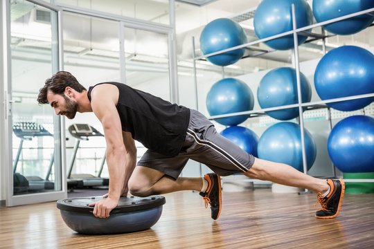 Serious man doing exercise with bosu ball