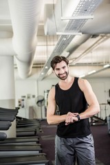 Fototapeta na wymiar Smiling man on treadmill looking at smartwatch
