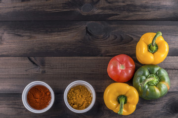green and yellow paprika with tomato and chili powder on wooden background