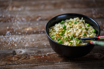 Bowl of noodles with fresh peas and chopped onion.