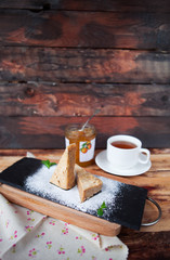 Sweet almond cake with cup of tea on old wooden background with