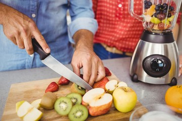 Midsection of couple preparing fruit juice