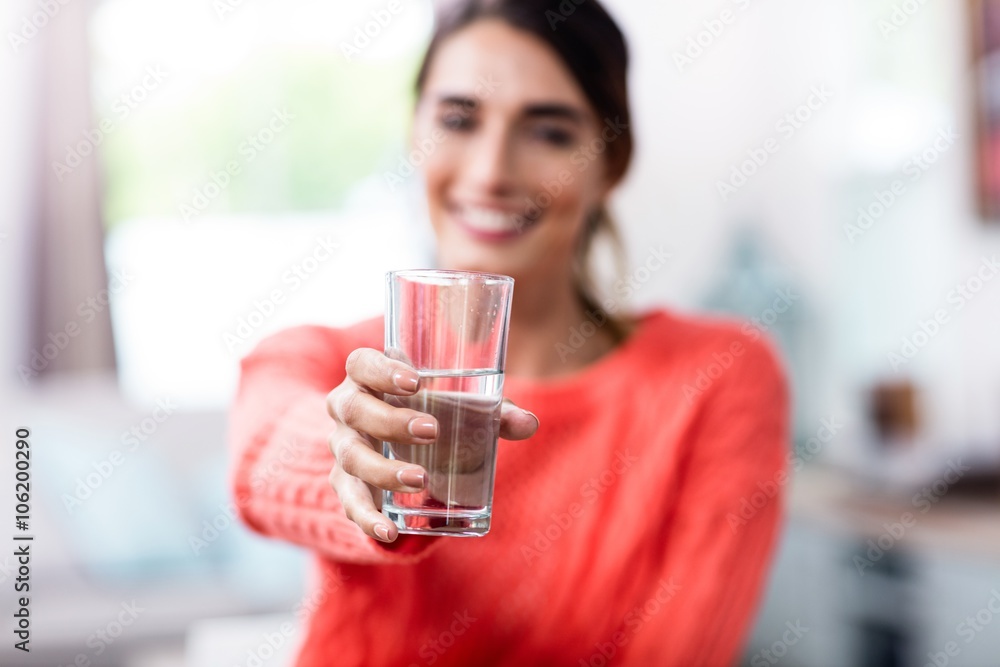 Wall mural young woman showing drinking glass with water