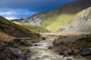 Glacier river in Iceland under the green hills, near Landmannalaugar