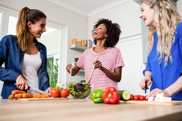 Young female friends laughing while preparing food