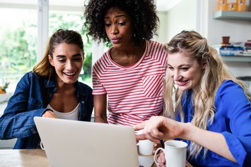 Female friends smiling while looking in laptop