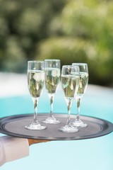 Cropped hands of waiter holding champagne flutes tray