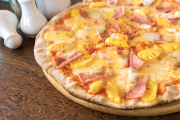ham and pineapple pizza on wooden table