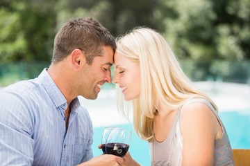Smiling couple with eyes closed while toasting red wine 