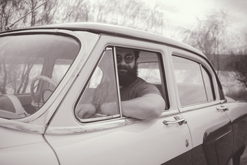 Obraz premium Bearded man behind the wheel of a retro car